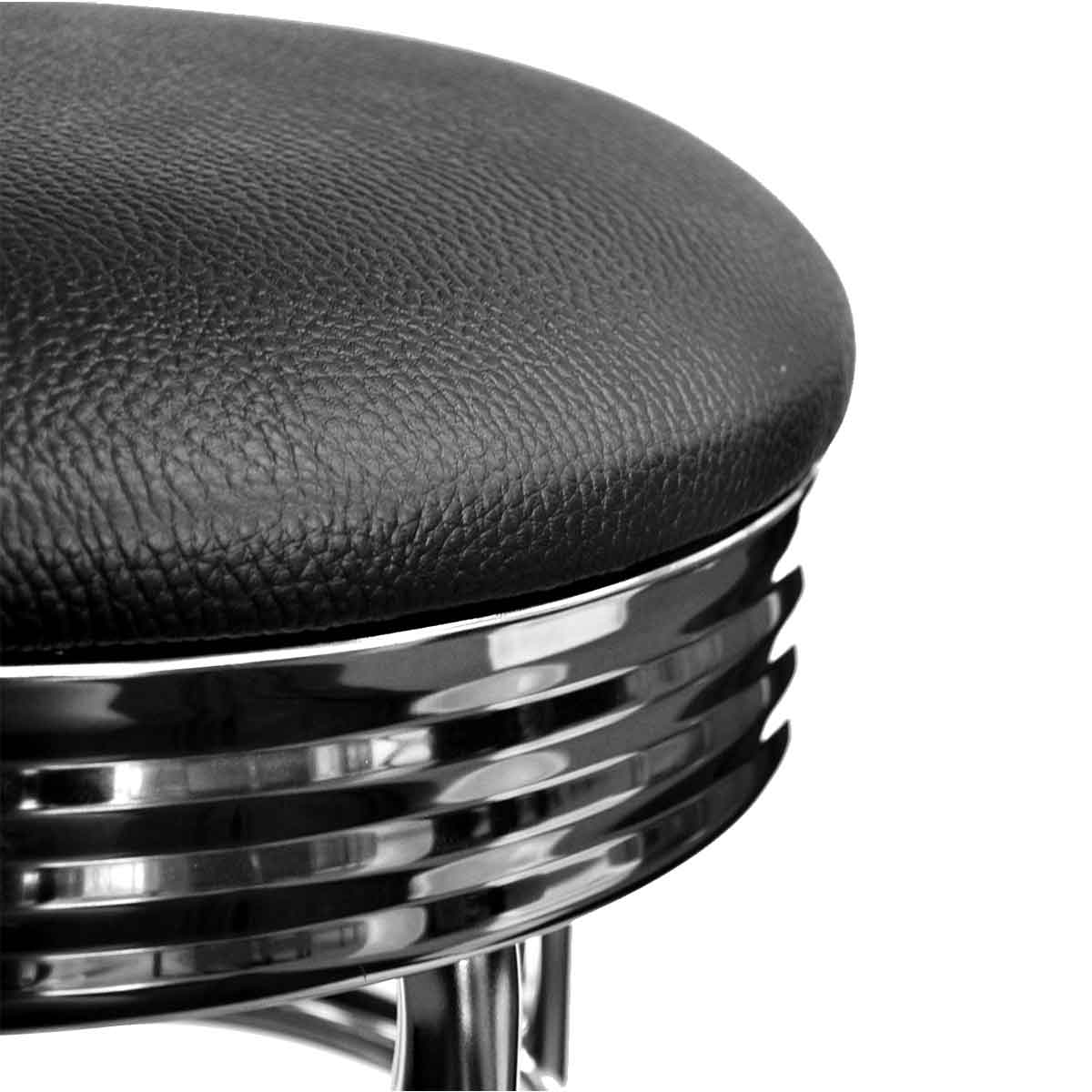 A close-up shot shows the round, black, textured leather seat and chrome-banded sides of a bar stool. The shiny chrome reflects light, contrasting with the matte finish of the seat.