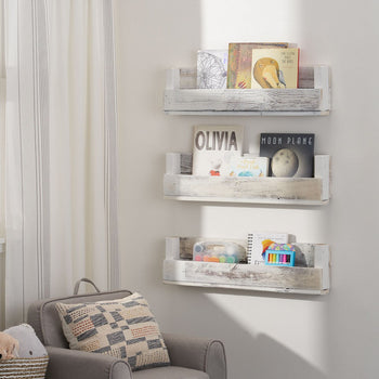 Three-tiered set of floating nursery shelves in rustic whitewashed wood are mounted on a white wall in a child's room. Each shelf displays different books and decorative items.