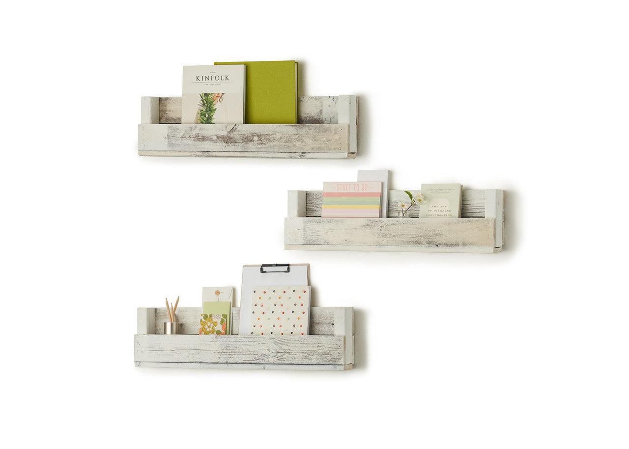 Three reclaimed wood shelves are mounted on a white wall in a staggered arrangement. Each shelf holds books and decorative items, showcasing their functionality as children's bookcases or display shelves.