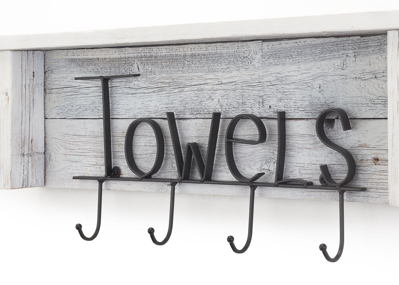 A close-up shot shows a rustic white wooden shelf with a distressed gray wood backing. Black metal lettering spells out "Towels" above four hanging hooks.