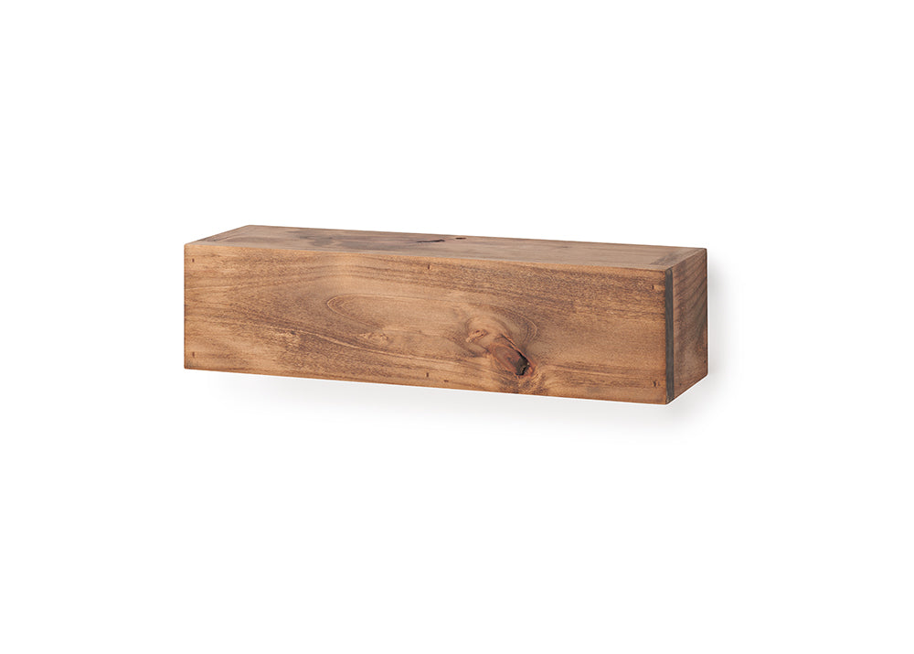 A rectangular, floating wooden shelf with a natural grain and warm brown finish is mounted against a plain white wall. The shelf is shown completely empty, highlighting its smooth top surface, organic wood knots, and clean block design.