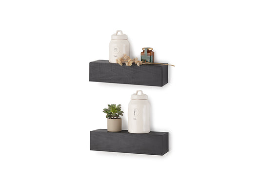 Two black-colored floating block shelves are mounted on a white wall, displaying white ceramic jars, a small potted succulent, and a decorative sprig. The shelves feature a subtle wood grain texture and are arranged vertically in a staggered, modern style.