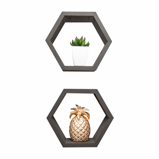 Two black hexagonal wall shelves are mounted on a white background. The top shelf holds a small green succulent in a white pot, while the bottom shelf features a decorative gold pineapple ornament.