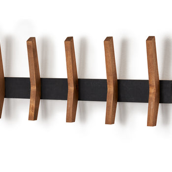 A horizontal black rectangular rack is mounted on a white wall, featuring five evenly spaced wooden pegs that jut out diagonally. The pegs have a flat, angled design, suggesting a mid-century modern aesthetic.