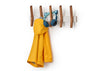 A wooden wall rack with five angled hooks holds a bright yellow raincoat and a pair of blue cat-ear headphones. The background is white, making the items stand out clearly.