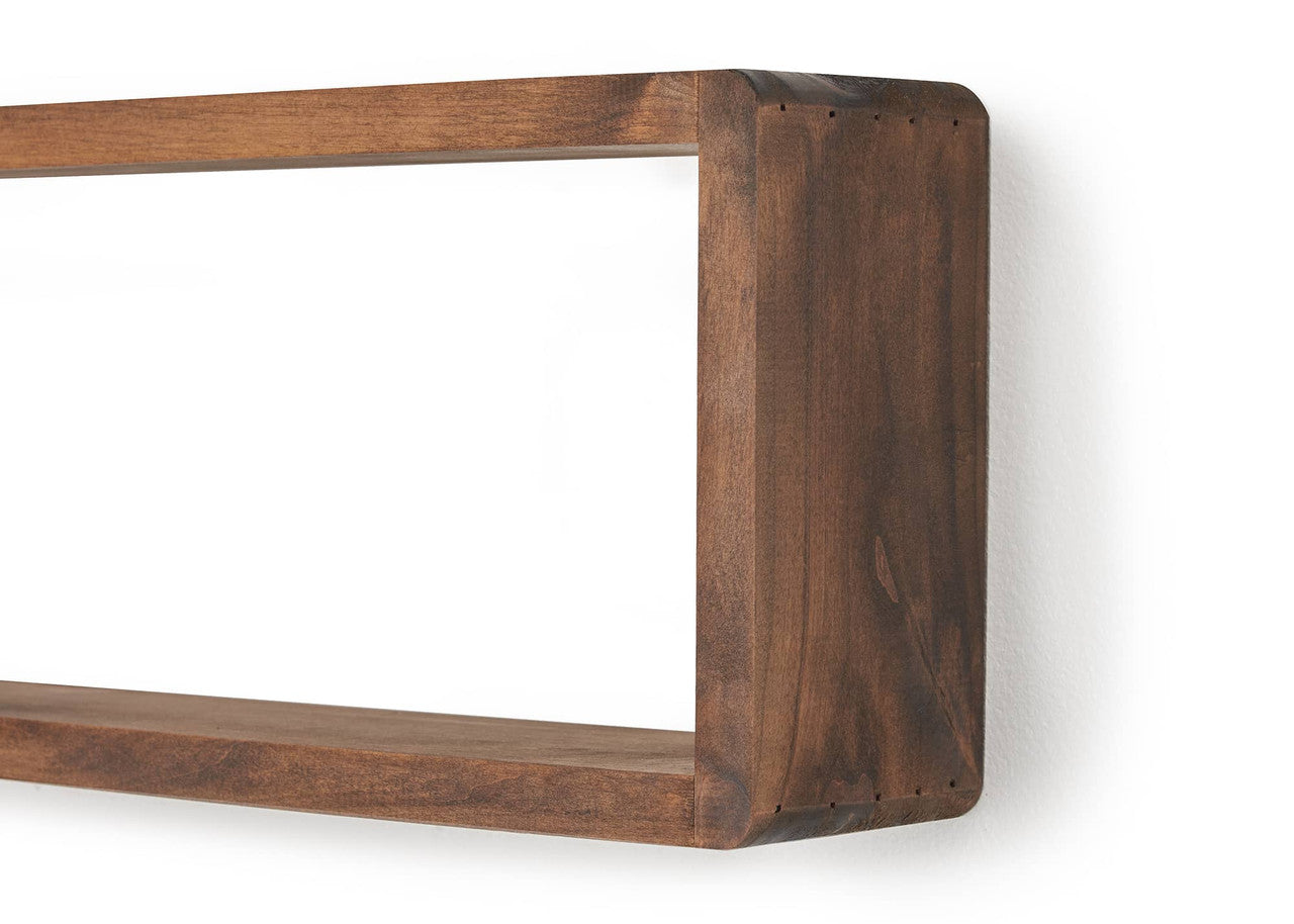 A close-up shot of a stackable floating box shelf mounted on a white wall, casting a subtle shadow. The wooden shelf has a rich brown tone and a rectangular opening, showcasing its minimalist and functional design.