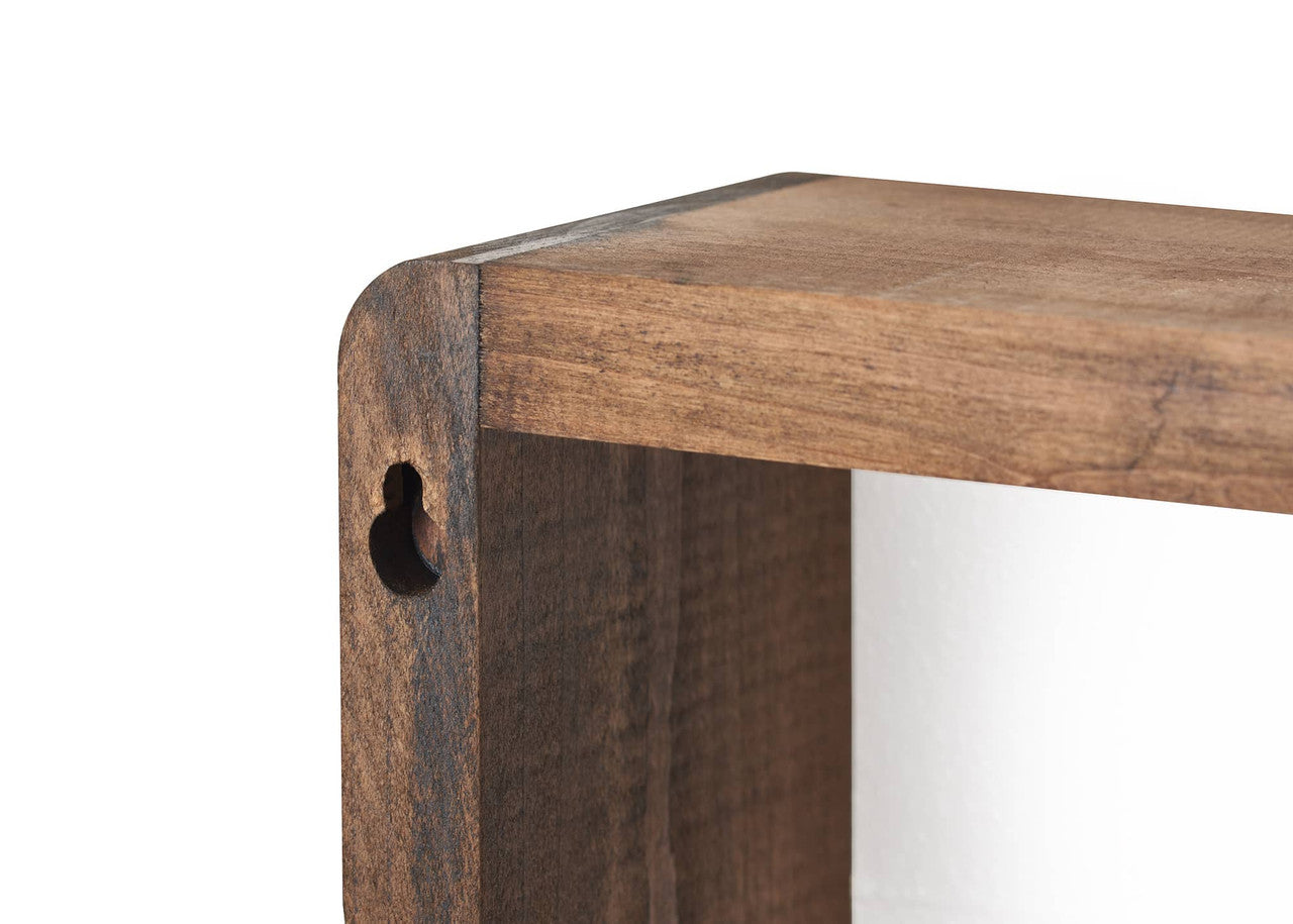 A close-up shot shows the corner of a wooden floating box shelf. The shelf has a warm brown stain and a keyhole slot for mounting is visible on the side.