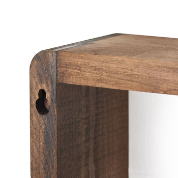 A close-up shot shows the corner of a wooden floating box shelf. The shelf has a warm brown stain and a keyhole slot for mounting is visible on the side.