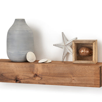 Contemporary farmhouse style floating shelf made of light-colored wood adds a rustic touch to a plain white wall. Decorative items including a vase and a starfish sit on the shelf.