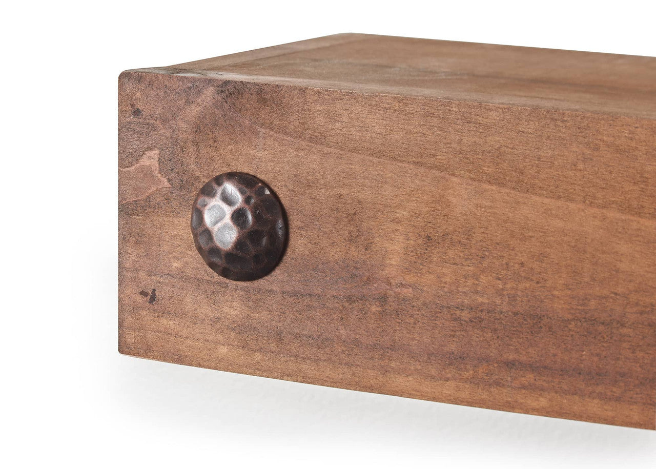 A close-up image of a wooden drawer or panel with a round, hammered metal knob in a dark, antique finish. The wood has a warm tone with visible grain patterns and a slightly rustic appearance.