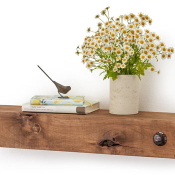 A wooden floating shelf holds a small stack of books titled 