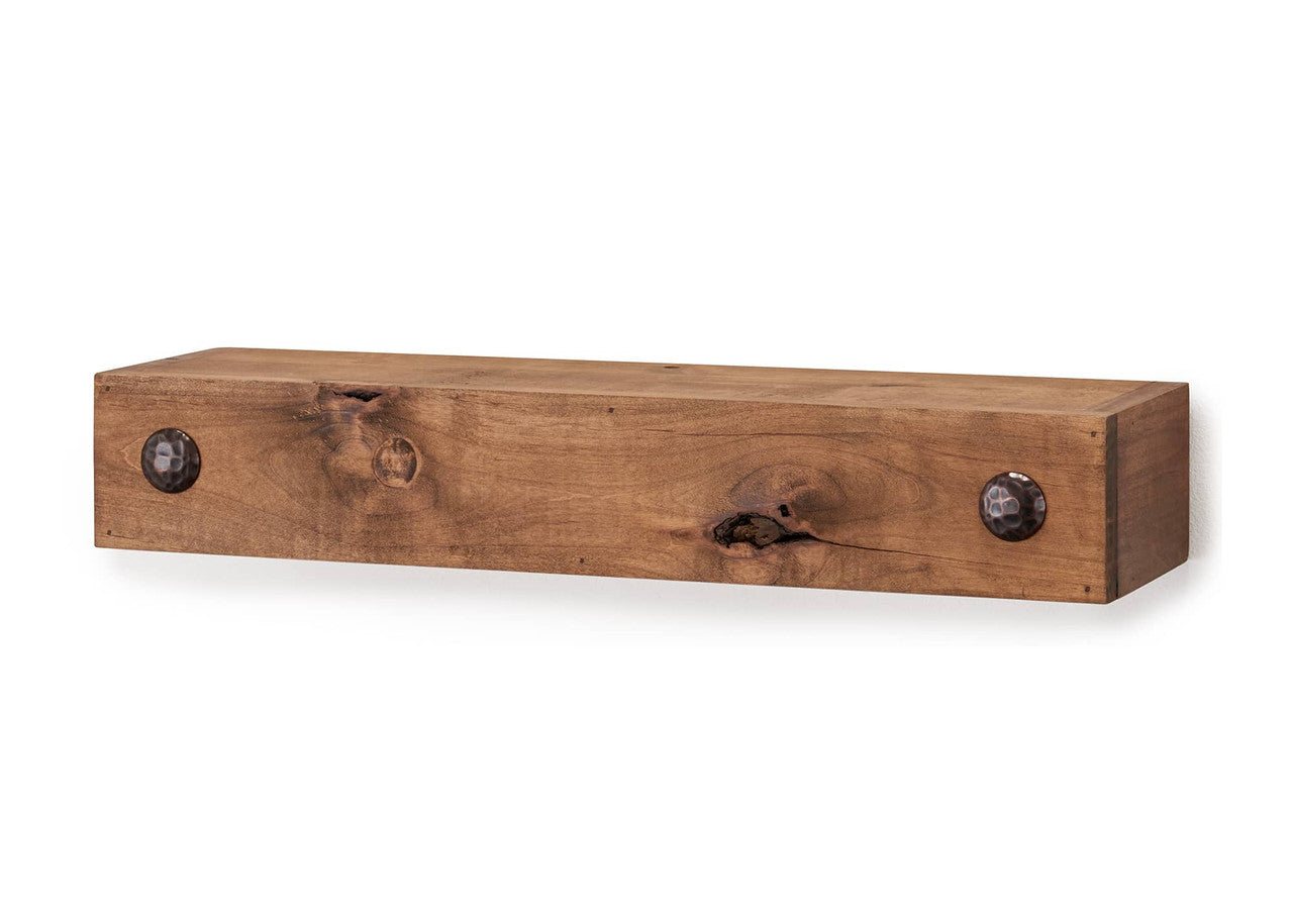 Close-up studio shot of a rustic wooden floating shelf with a light, natural finish. Two prominent black clavos flank the front edge, highlighting the shelf's farmhouse style.