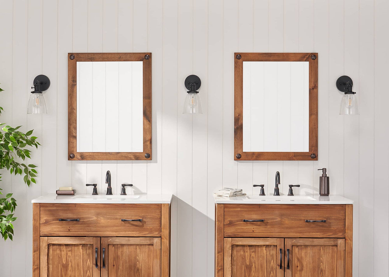 Two matching farmhouse-style vanity mirrors with wooden frames and clavos are mounted above double sinks in a bathroom setting. The mirrors reflect the white walls and enhance the room's rustic charm.