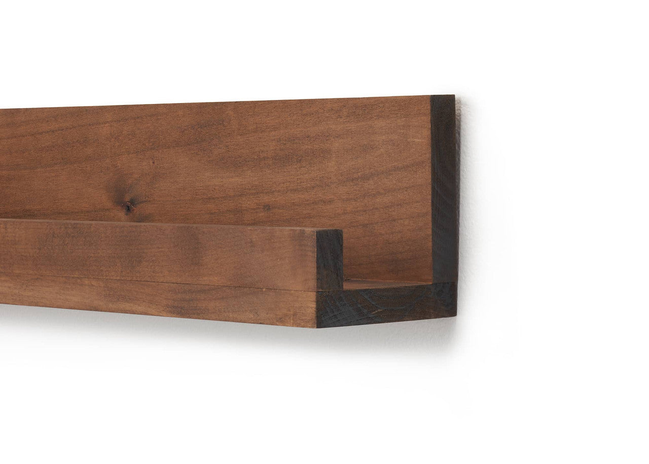 A close-up shows a long, narrow, dark brown wooden floating shelf mounted on a white wall. The shelf has a raised front lip to hold items in place.