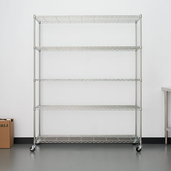 A five-shelf, rolling, wire shelving unit stands centered against a white wall in what appears to be a commercial kitchen or storage area. To the right is a stainless steel table, and two small cardboard boxes sit on the floor to the left.