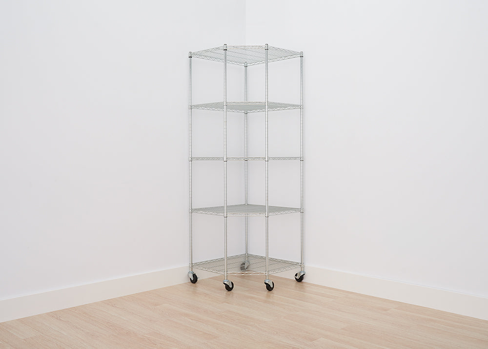 A five-tier, chrome wire shelving unit with a corner design stands on a light wooden floor, positioned against two white walls. The unit includes caster wheels for easy mobility and maximizes storage space in the corner of a room.