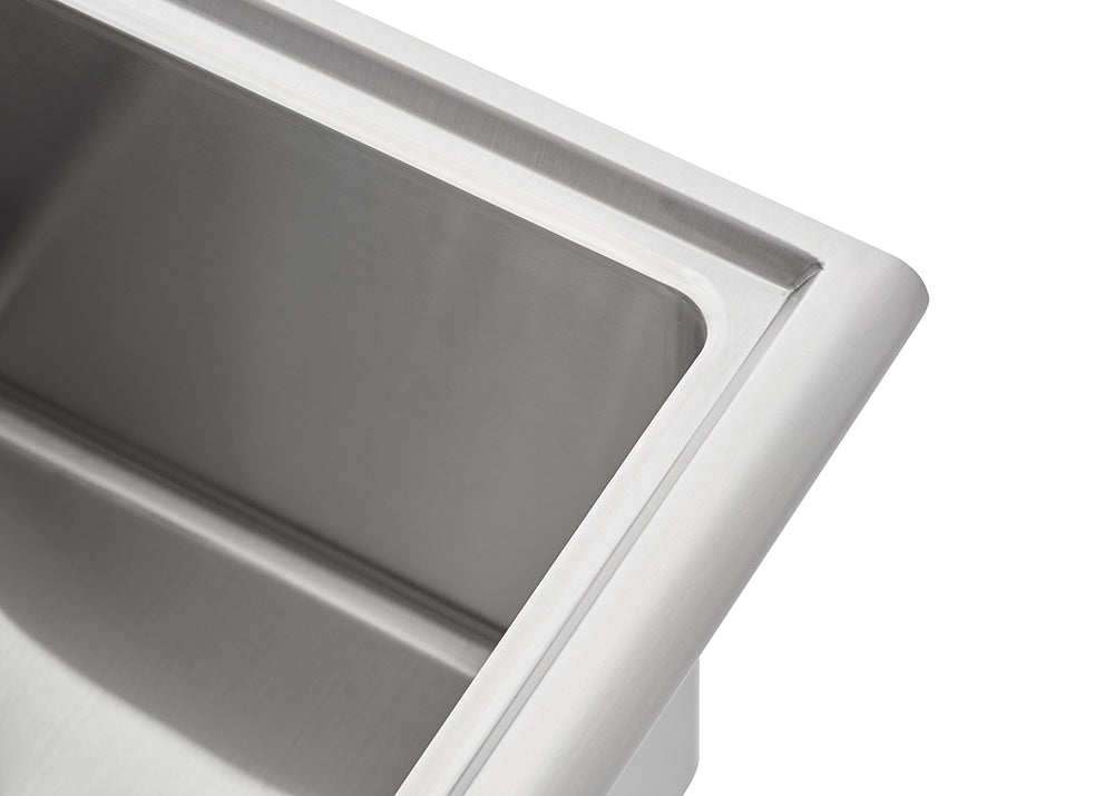 A close-up shot shows the corner of a brushed stainless steel sink. The image highlights the smooth, rounded edge of the rim and the clean, polished interior of the basin.