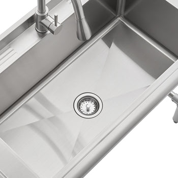 A stainless steel utility sink with a single large basin is shown from a high angle. The sink features a modern pull-down faucet on the back ledge, which also has a grooved section, and is mounted on metal legs.