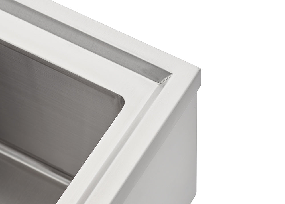 A close-up photograph shows the corner of a stainless steel sink or drop-in cooler, highlighting the brushed metal finish on the inner basin and the smooth rim. The design features a recessed channel or ledge just inside the top edge.
