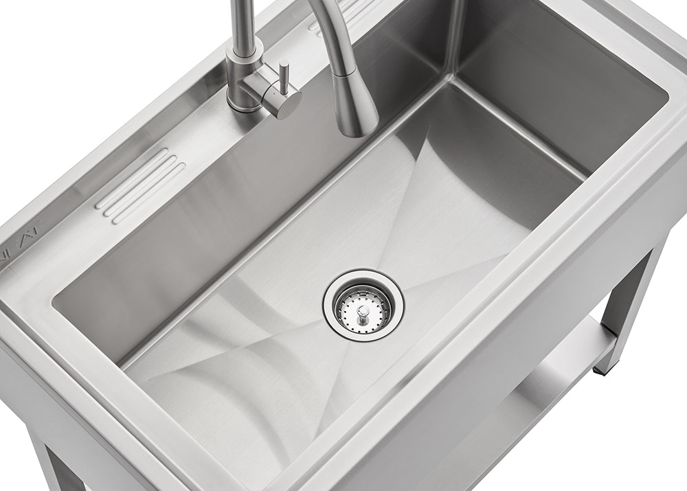A top-down view of a modern stainless steel kitchen sink with a single large basin. The sink features a faucet with a pull-down sprayer and an integrated drainer area to the left.