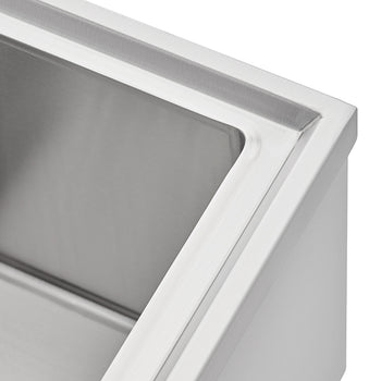 A close-up shot shows the corner of a stainless steel sink basin. The image focuses on the clean, brushed metal finish and the precise, angular edge of the sink's rim.