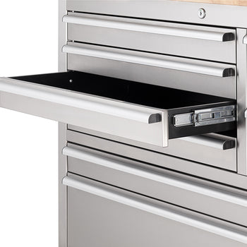 A close-up shot focuses on an open drawer of a stainless steel tool workbench, showing the smooth metal ball-bearing slide mechanism along its side. A cylinder key lock is visible above the top drawer.