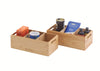 A front three-quarter view displays two natural bamboo storage bins, one wider with four internal compartments and a smaller one with two, positioned against a plain white background. The bins are filled with assorted pantry items including spice tins, cocoa powder, chocolate bars, and glass jars, and feature integrated handles and "NEAT" branding.