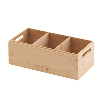 A three-compartment bamboo organizer box with open top is shown in a three-quarter view. It features an engraved 'NEAT' logo on the front panel and two cut-out handles on the sides for easy transport.