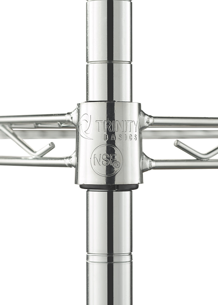 A close-up photograph focuses on a chrome metal leg joint from a wire shelf. The cylindrical connector is stamped with the "Trinity Basics" logo and a circular "NSF" mark, and it connects vertical posts with horizontal wire shelving that extends to the left and right.