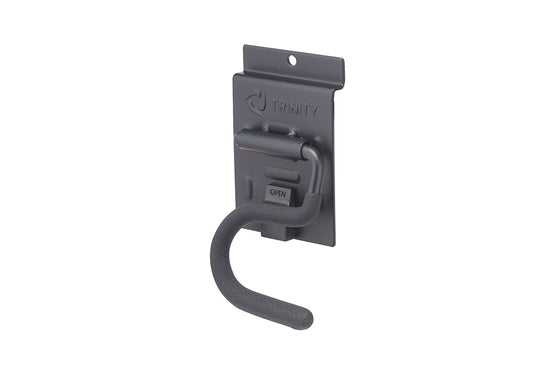 A dark gray metal garage storage hook features a curved, textured arm designed for hanging tools or equipment. It is mounted on a matching rectangular backplate displaying the embossed "TRINITY" logo at the top and a small latch labeled "OPEN."