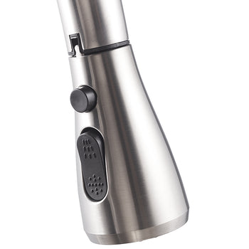 A close-up photograph shows the brushed stainless steel sprayer head of a kitchen faucet. It features a black, rubberized toggle switch for spray pattern selection and a small, round black button above it, likely for a pause or boost function.