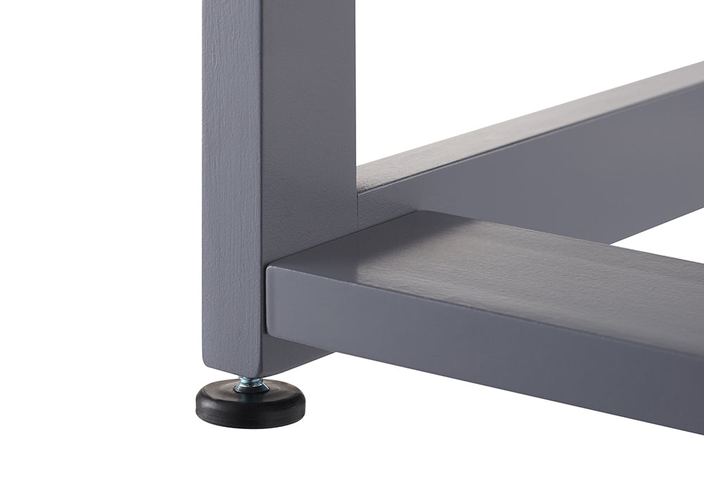 A close-up shot focuses on the bottom corner of a gray furniture frame, showing the intersection of three square beams. A small, black adjustable leveling foot is screwed into the base of the vertical leg to provide stability.