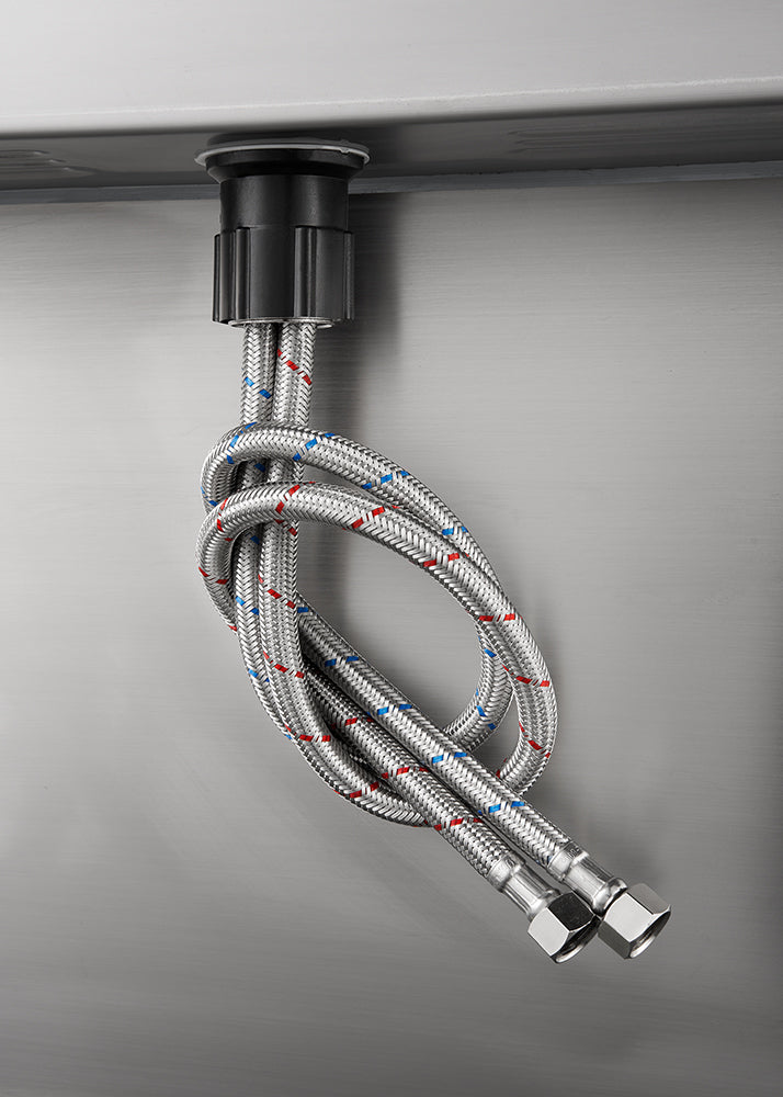 Two stainless steel braided flexible water supply hoses, one marked with a red stripe and one with a blue stripe, are attached to the base of a faucet on the underside of a sink or countertop. The hoses are tied in a loose knot and hang down, ending in metal female connectors.