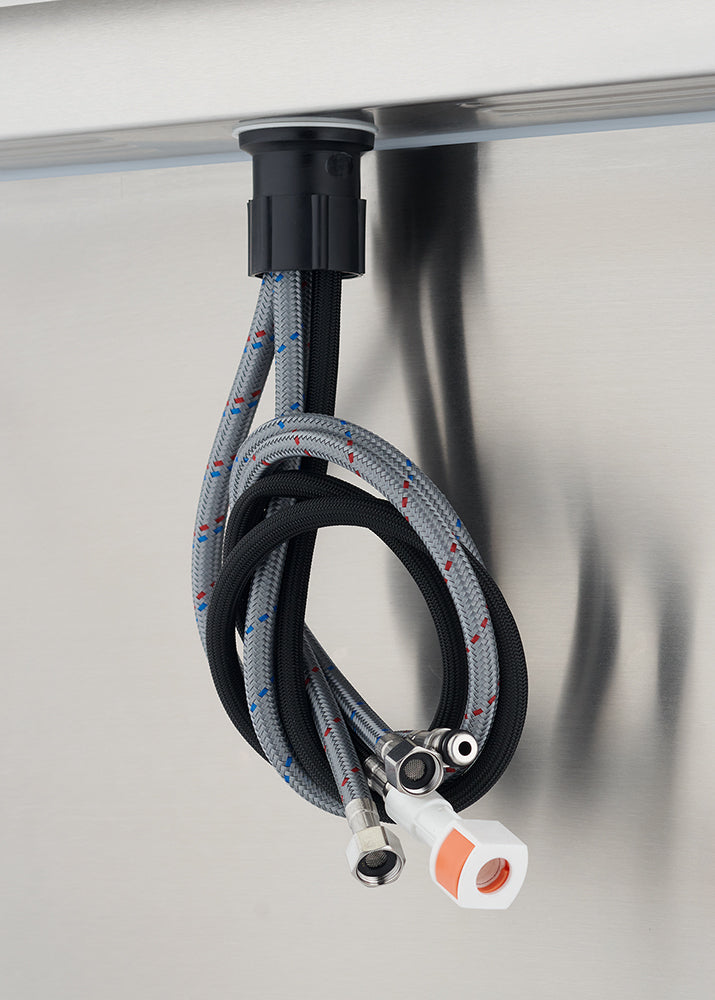 A close-up view from below shows a set of braided, flexible water supply hoses and a black pull-out hose hanging beneath a stainless steel surface, likely for a faucet installation. The hoses feature metal connectors and a distinctive white and orange quick-connect fitting.