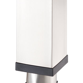 A close-up photograph focuses on the bottom end of a square, brushed metal furniture leg, likely stainless steel. The leg is capped with a black plastic foot or glider that transitions to a smaller, angled metal cylinder at the very base, which is also capped with black plastic.