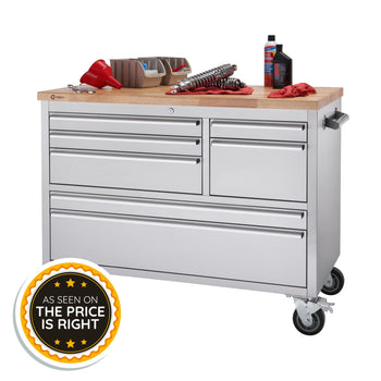 A stainless steel rolling workbench with a wood top holds various automotive tools, including a red funnel, shocks, and storage bins. The bottom left corner features a circular 