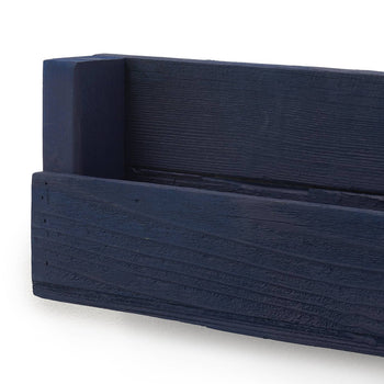 A close-up shot shows a dark blue wooden shelf, angled to highlight its rustic texture and the joinery of the sides and back. The depth of field blurs the background, focusing attention on the craftsmanship and color of the shelf.