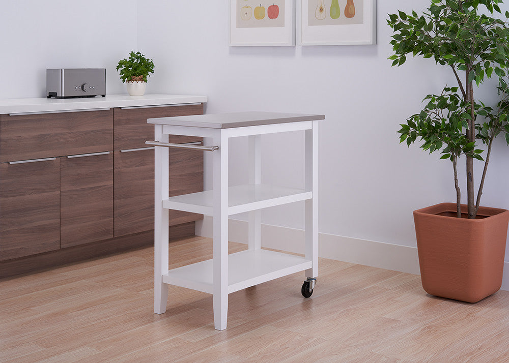A white, three-tiered kitchen cart with a light gray top and a towel bar is positioned in a kitchen. The cart has wheels and is placed between a brown cabinet and a potted plant.