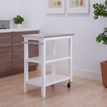 A white, three-tiered kitchen cart with a light gray top and a towel bar is positioned in a kitchen. The cart has wheels and is placed between a brown cabinet and a potted plant.