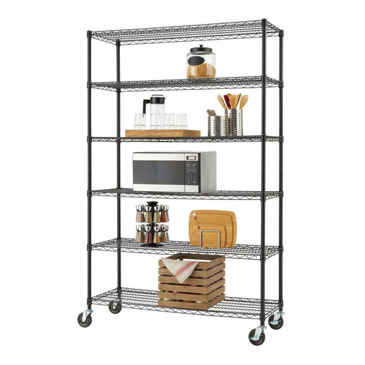 A six-tier Trinity Basics wire shelving unit in black, equipped with wheels, holds various kitchen and pantry items. The shelves display a microwave, spice rack, cutting boards, glassware, a jar of oats, and a wooden crate with a towel.