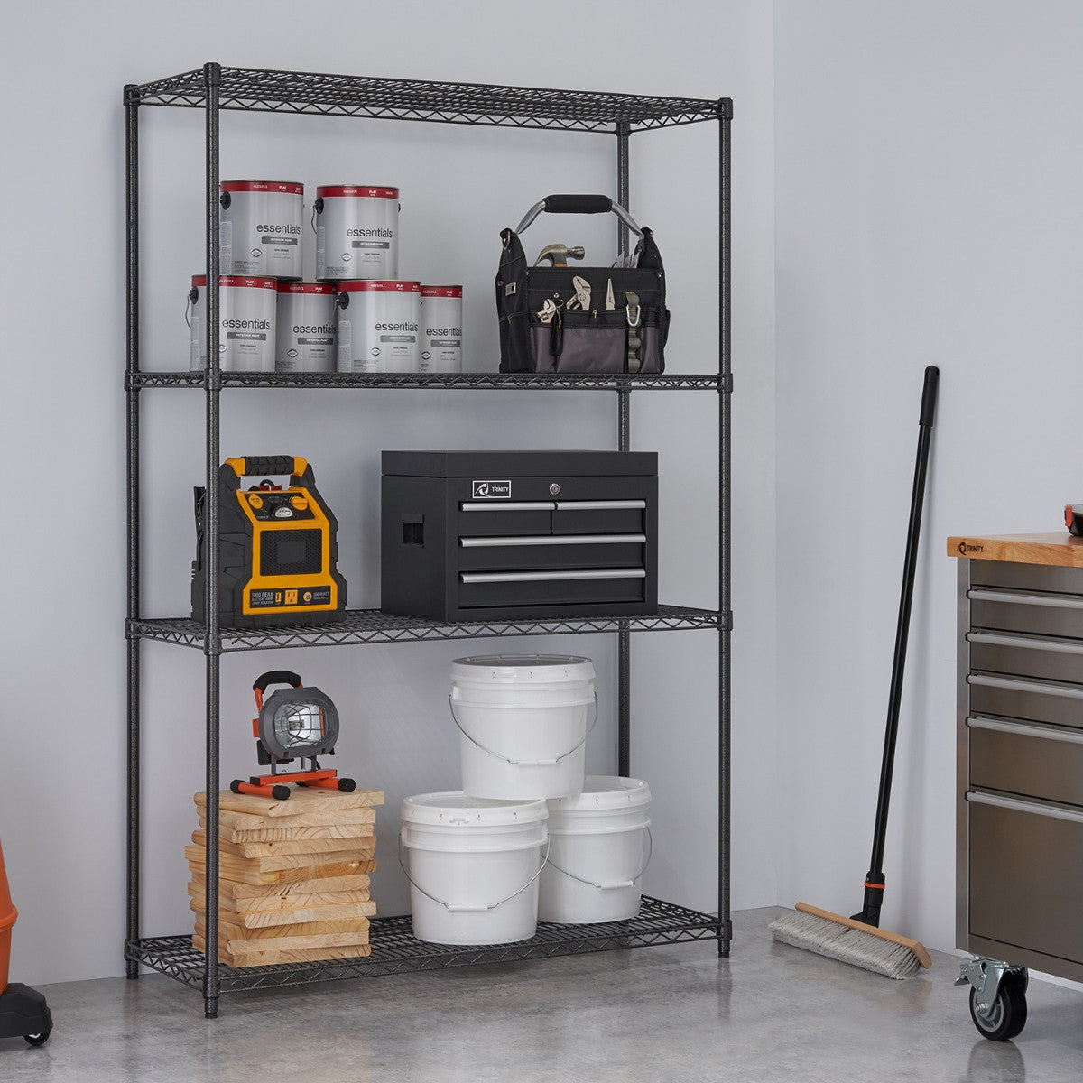 A black anthracite wire shelving rack used in garage filled with paint cans, tools boxes, and other garage items.