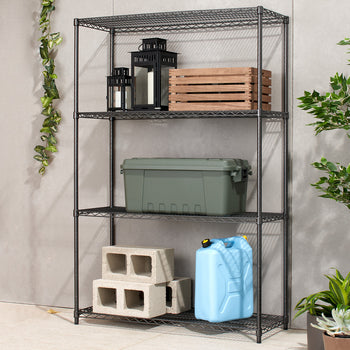 A four-tier black wire shelving unit stands against a light gray tiled wall. The shelves hold various items including lanterns, a wooden crate, a green storage bin, concrete blocks, and a blue water jug.