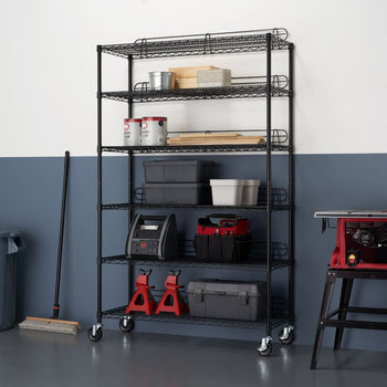 A tall, black wire shelving unit with six tiers stands against a two-toned wall, the lower half painted a deep blue and the upper half white. The shelves are filled with various storage containers, tools, and supplies, and the unit rests on wheels.
