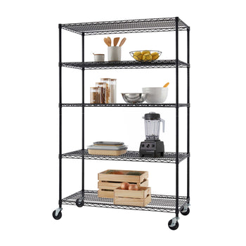 A tall black wire shelving unit on caster wheels holds kitchen essentials, including utensils, fruit, storage jars, bowls, a blender, and stacked dishes. Wooden crates with produce are stored on the bottom shelf, providing additional organized storage.