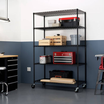 A black, five-tier wire shelving unit on wheels is shown against a two-toned wall, holding various storage items like toolboxes and wooden crates. The shelving unit appears sturdy and functional for organizing items in a garage or similar space.