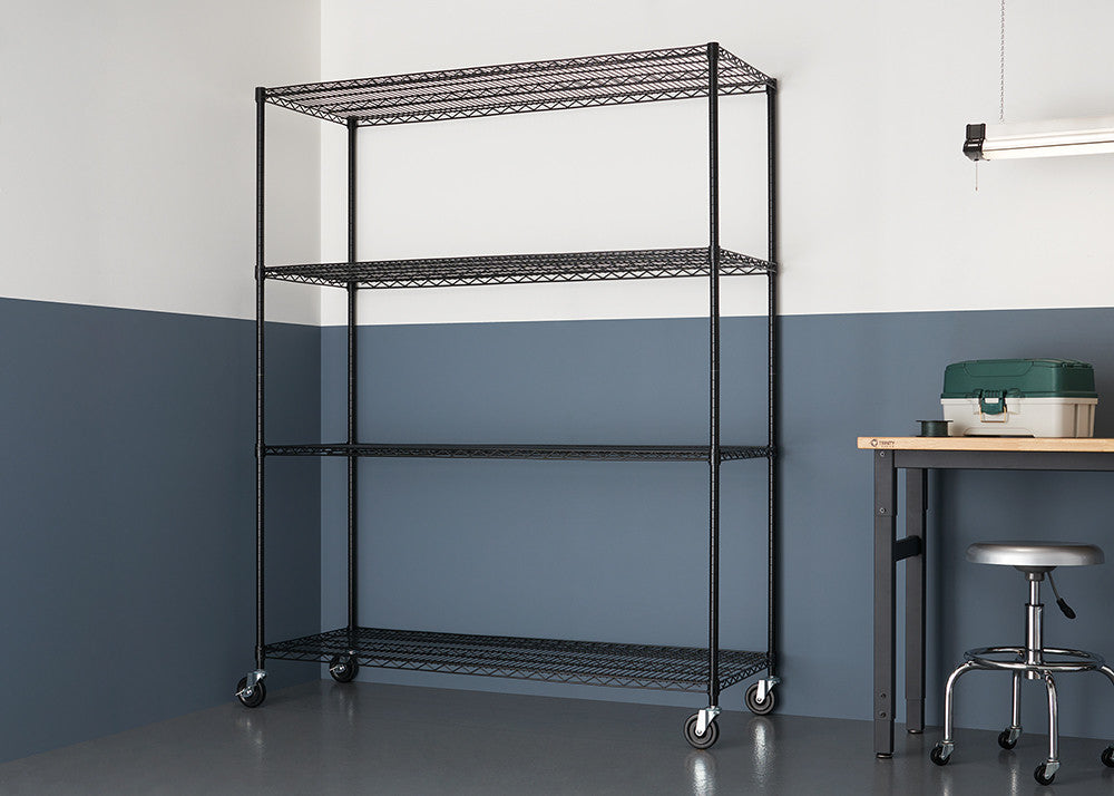 A black, four-tier wire shelving unit with wheels is shown against a two-tone gray and white wall. A workbench with a toolbox and a stool are partially visible to the right.