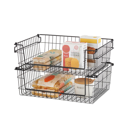 A white background studio shot of two black wire stackable baskets, each filled with various packaged food items. The baskets are stacked one on top of the other, showcasing their stackable design.