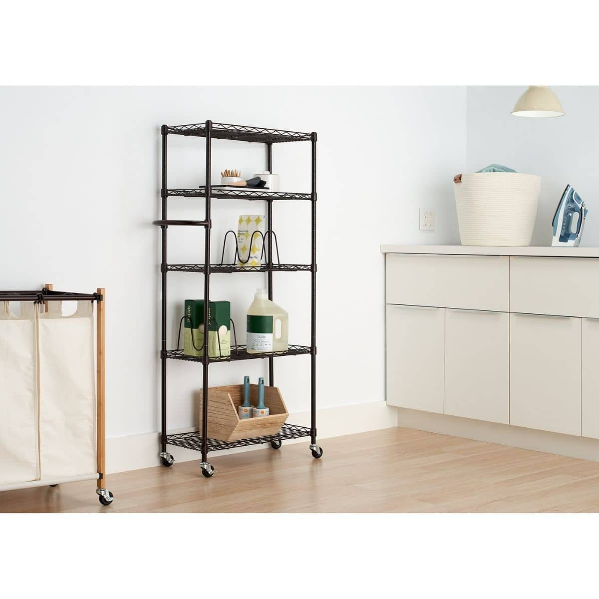 A Trinity 5-Shelf Steel Bronze Pantry Organizer with Shelf Dividers. The organizer is black and has five shelves, with various items stored on them, including bottles, boxes, and a wooden bin.
