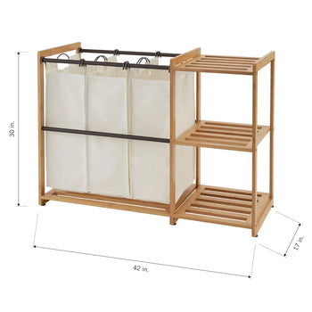 A light-wood-framed laundry sorter with three separate white laundry bags hanging from a metal rod. To the right of the bags, there are two slatted shelves, and the overall dimensions of the unit are 42 inches wide by 30 inches tall by 17 inches deep.