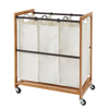 A Laundry Cart with a wooden frame and three removable, natural-colored canvas bags hanging from a metal rod. The cart is on wheels, and there's an additional bronze horizontal metal bars across the frame for stability.